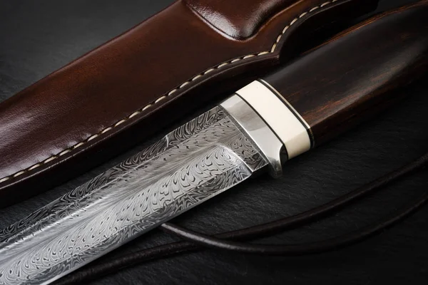 damascus knife next to its protectvive sheath